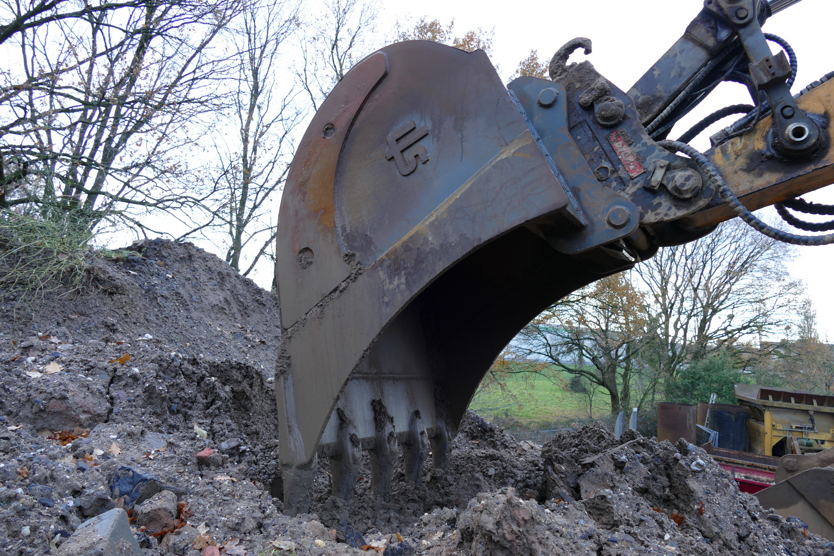 Die Nahaufnahme des KLIS Baggerlöffels wie er im Begriff ist in den Schuttberg einzutauchen
